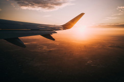A picture presents an airplane wing above the landscape at sunset.