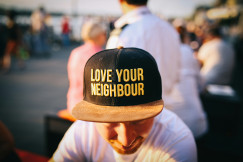A photo presents a person wearing a “Love Your Neighbour” cap.