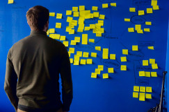 A photo presents a person reviewing notes on a planning board.