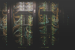 Photo presenting server racks with illuminated network cables and data center equipment.