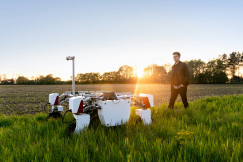 A photo presents a person inspecting agricultural technology in a field.