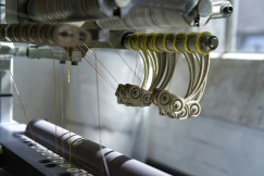 Close up of an industrial textile machine processing multiple yarns, illustrating advanced manufacturing technologies used in the production of smart and functional textiles.