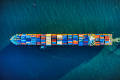 A photo presenting an aerial view of a container ship sailing across the sea.