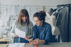 Two designers collaborate, reviewing plans with smiles.