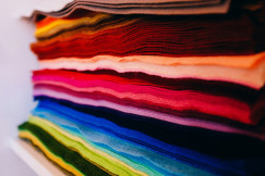 Stack of colourful textile fabrics in red, pink, orange, blue, green and neutral tones