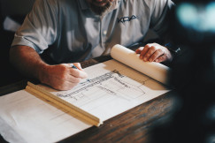 The picture describes an architect reviewing building plans.