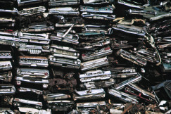 The photo presents a pile of old cars.
