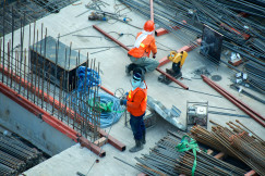 The image shows construction workers and building materials on a construction site.