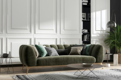 Modern living room with a green upholstered sofa, decorative cushions, a patterned rug and contemporary interior accessories.