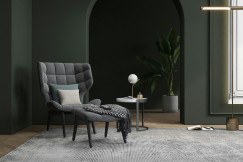 Modern interior featuring an upholstered armchair, cushions, a textile throw and a large woven rug in a contemporary living space.