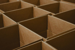 The photo presents a close-up of empty cardboard boxes arranged in rows.