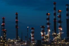 The photo presents an industrial refinery at night.