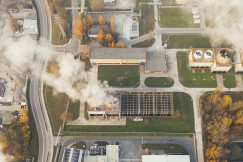 The photo presents an industrial facility releasing steam.