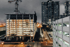 The picture presents a high-rise building under construction with cranes overhead.