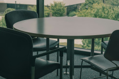 The photo presents a meeting table with chairs.