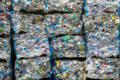 The photo presents compressed plastic bottles ready for recycling.