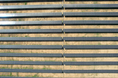 The photo presents rows of solar panels in a large solar farm.
