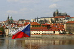 The photo presents the Czech flag with Prague in the background.