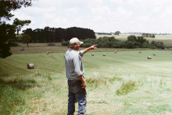 The photo presents a farmer standing in a field.