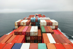 The photo presents a container ship carrying cargo at sea.