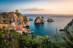 The photo presents a rocky coastline with clear blue sea.