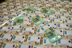 The photo presents stacks of €100 and €200 euro banknotes.