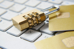 The photo presents a combination lock and credit cards on a computer keyboard.