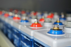 The photo presents a row of industrial battery cells with electrical terminals, illustrating battery storage and energy technology.