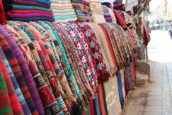 Colourful textiles and patterned fabrics displayed at a fashion market.