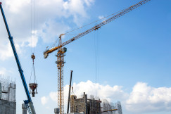 The picture describes a large-scale construction site where tower cranes and lifting equipment are being used to build a reinforced concrete structure.