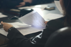 The picture describes a person sitting at a table and reviewing printed documents.