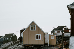 The image showcases a prefabricated house situated on rocky terrain in a remote settlement.