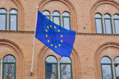 An European flag flying in front of a brick building.