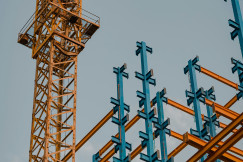 The picture describes a construction site featuring a tower crane and an exposed steel frame structure.