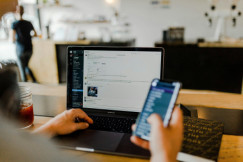 A photo presenting a person using a laptop and smartphone at a workspace