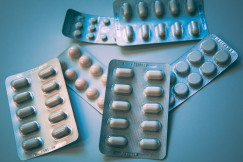 The photo presents several blister packs of assorted tablets and capsules arranged on a blue surface.