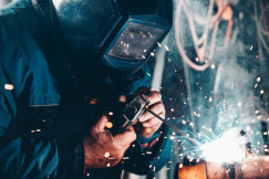 The photo presents a welder working with metal.