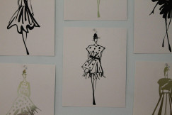 Fashion illustrations of dresses and outfits pinned to a wall, representing fashion design, creativity and collection development.