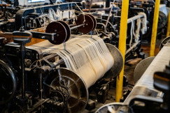 Industrial weaving machinery processing yarn in a textile production facility.