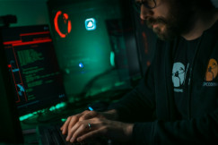 The photo presents a person working on cybersecurity at a computer.