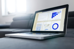 The photo presents a laptop displaying web analytics dashboards with charts, a user-retention cohort grid, a world map and a device breakdown.