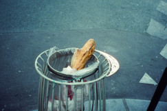 The photo presents baguettes discarded in a street rubbish bin.