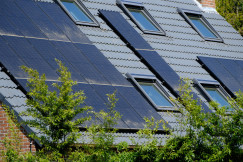 The picture describes a modern residential building featuring a grid of windows and integrated photovoltaic elements.