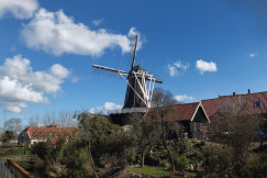 The picture describes a traditional windmill situated within a rural village setting.