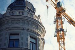 The picture describes the restoration or redevelopment of a historic urban building alongside modern construction activity.
