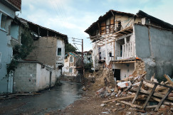 The picture describes a street lined with severely damaged residential buildings.