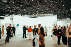 Visitors walking through a large exhibition hall with illuminated booths and displays during a professional trade fair.