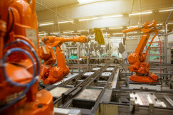 The photo presents robotic arms in a factory.