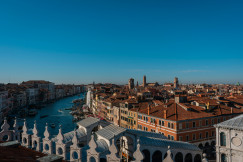 Aerial view of Venice, Italy, showing the Grand Canal winding between historic buildings and the Rialto Bridge. 