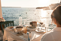 The photo presents a meal by the sea at sunset.